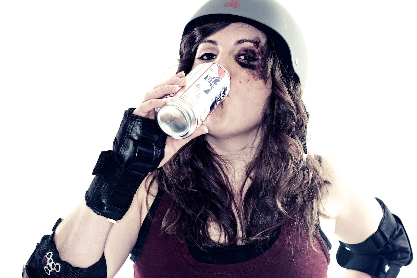 A roller derby woman with a black eye drinks a Pabst Blue Ribbon beer.