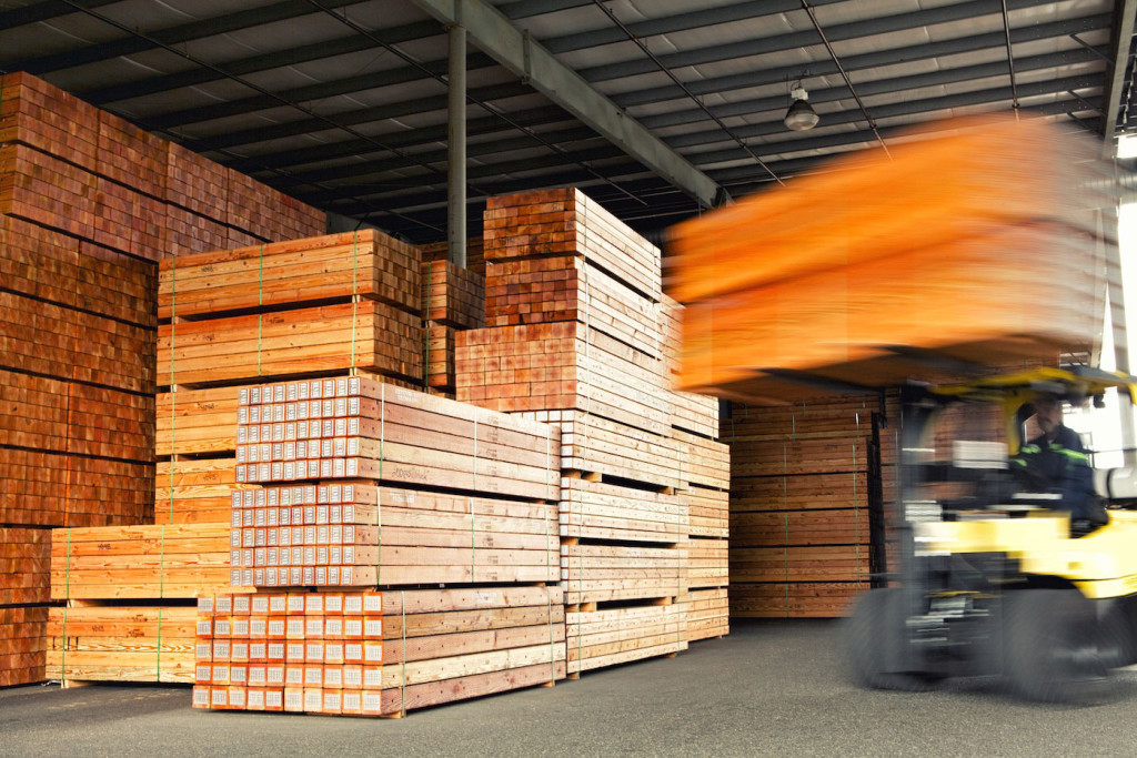 A forklift moves a pile of wood crossarms.